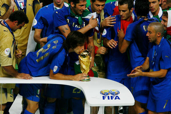 Andrea Pirlo kisses the FIFA World Cup trophy, standing alongside former Sydney FC player Alessandro Del Piero