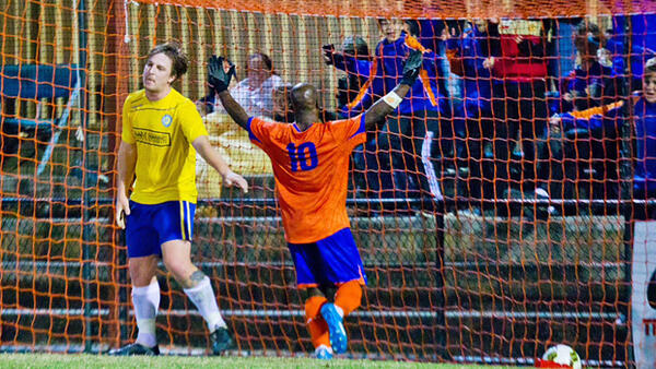Lions FC's Kado Aoci celebrates scoring in front of a group of supporters. Image: Ian Judd – FB Media / Football Brisbane